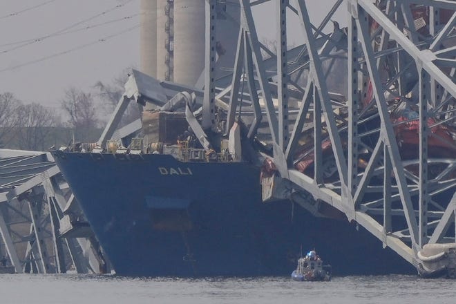 A container rests against wreckage of the Francis Scott Key Bridge on Tuesday, March 26, 2024, as seen from Sparrows Point, Md. The ship rammed into the major bridge in Baltimore early Tuesday, causing it to collapse in a matter of seconds and creating a terrifying scene as several vehicles plunged into the chilly river below. (AP Photo/Matt Rourke)