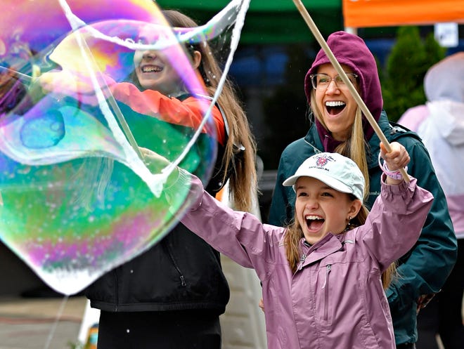 Jen Wile, back, and her daughter Lucy Wile, 9, of Spring Garden Township, react as they create a large bubble, provided by York’s Bubble Lady Debbie Flaum, during Go Green in the City in downtown York City, Saturday, April 27, 2024. (Dawn J. Sagert/The York Dispatch)