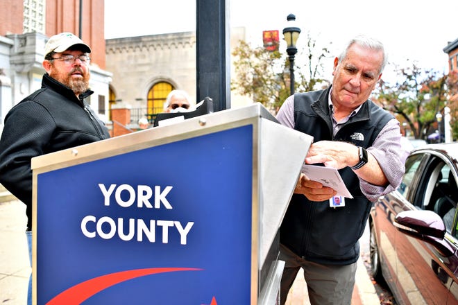 Richard Beaverson, left, with York County Parks, looks on as Les Shaffer, who manages juries as tip staff with York County courts, deposits a ballot dropped off during Election Day in York City, Tuesday, Nov. 7, 2023. (Dawn J. Sagert/The York Dispatch)