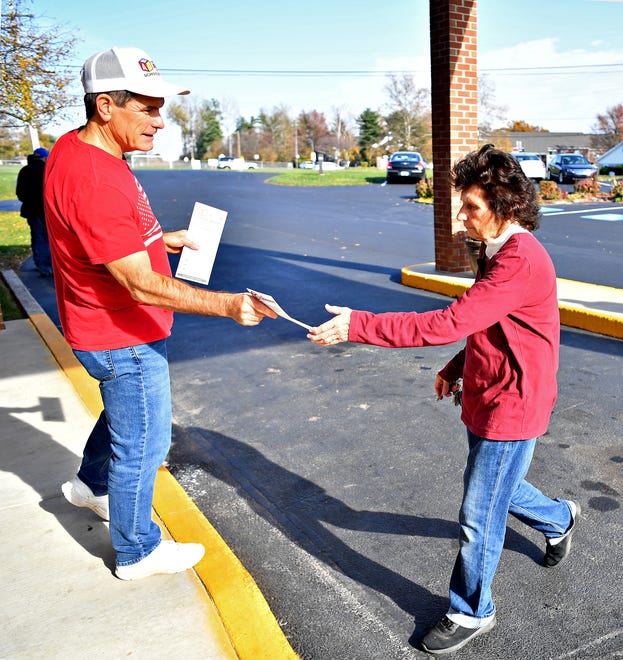 School board candidate Allen Hogan, left, hands voting information to voters outside their New Creation Community Church polling location during Election Day in Dover Township, Tuesday, Nov. 7, 2023. (Dawn J. Sagert/The York Dispatch)