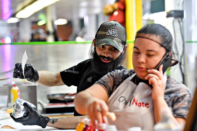 Owner Nathaniel Jamison, back, communicates with his eldest sister Aaliyah Jamison as they work together at The Breakfast Store inside Penn Market in York City, Saturday, Feb. 17, 2024. (Dawn J. Sagert/The York Dispatch)