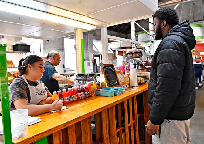 Aaliyah Jamison, left, assists customer Ohsajid Beard, of York City, with his first order at The Breakfast Store inside Penn Market in York City, Saturday, Feb. 17, 2024. (Dawn J. Sagert/The York Dispatch)