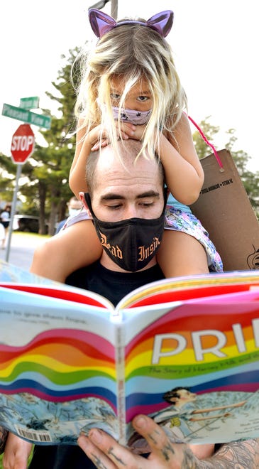 Greg McMillan reads a book about diversity to his daughter Mira, 4, during a demonstration outside the Central York School District Administration offices before a school board meeting there Monday, Sept. 13, 2021. The rally was in opposition to a banned resource list instituted by the district, which demonstrators say targets minority authors. Greg's wife Amelia is running for a seat on the Central York District School Board in the upcoming election. Bill Kalina photo